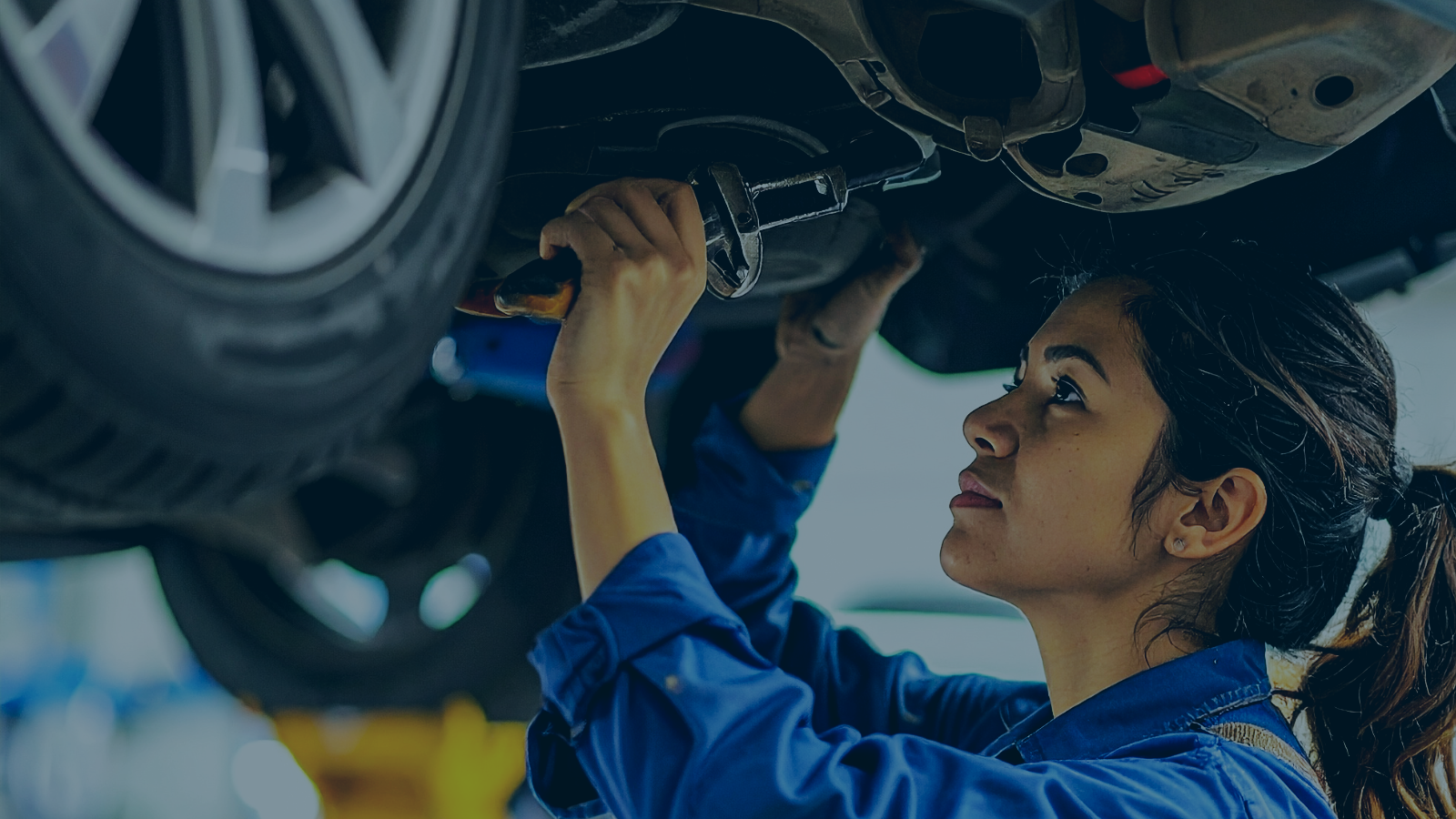 Vehicle technician working under a raised car in a Cardiff workshop